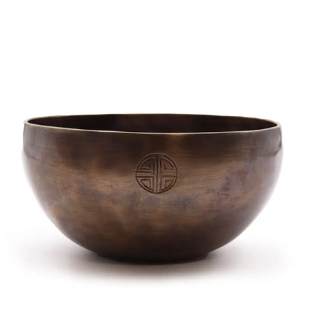 A bronze-colored hand-hammered large indian moon phase singing bowl with a subtle circular emblem near its rim