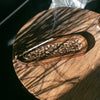 Large mango wood incense holder with hand carved floral patterns and a burning stick of mango wood incense inside