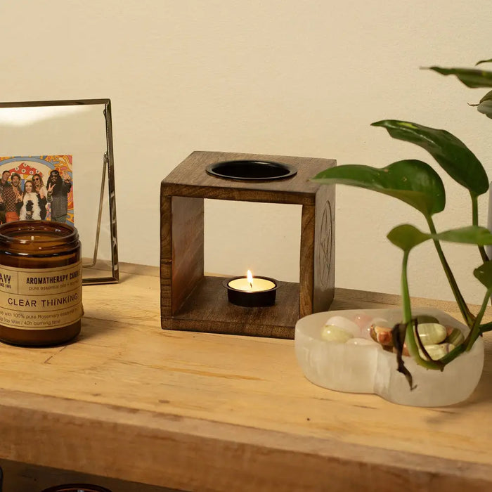 Large mango wood oil burner in dark wood cube shape with black top and lit tealight candle inside showing tree of life design