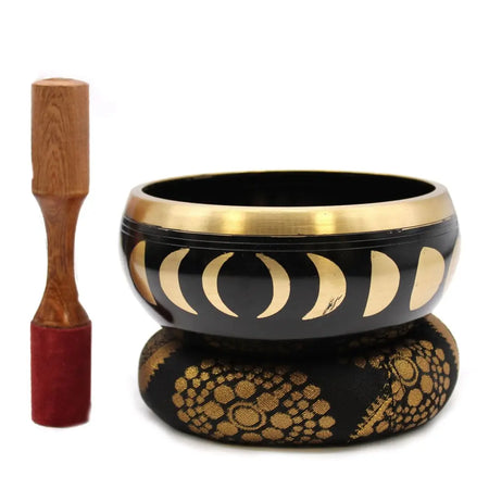 Black and gold large moon phase singing bowl set resting on patterned cushion to release negative emotions