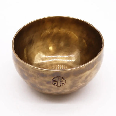 A large nepalese moon singing bowl in hand-hammered brass with a warm golden hue and geometric engraving