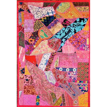 A large pink patchwork quilt wall hanging or table decoration made of colorful patterned fabric pieces