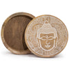 A large round wooden box with a white carved buddha face design on the lid in a whitewash finish