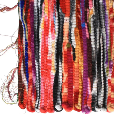 A large velvet dari rag rug with vibrant vertical stripes in red orange purple black and white made from handwoven materials