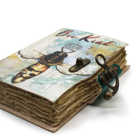 A rustic leather notebook with a distressed cover featuring a bee illustration and bee kind text secured by brass clasps
