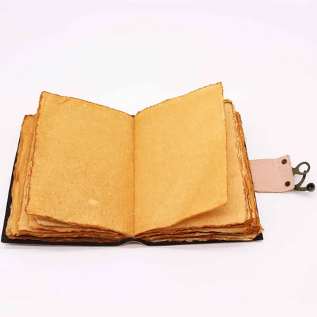 A leather notebook chakra journal with black cover, aged yellowish pages, deckled edges, and a pink leather bookmark holder