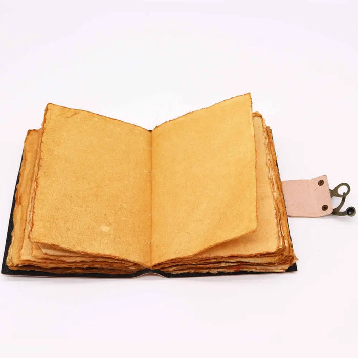 A leather notebook chakra journal with black cover, aged yellowish pages, deckled edges, and a pink leather bookmark holder