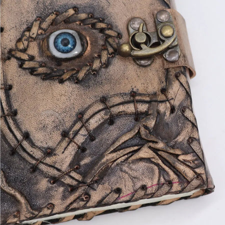 A rustic brown leather notebook with stitched evil eye design blue glass eyeball and antique brass hardware 7x5 inches