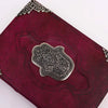 A rich burgundy leather notebook with a hamsa hand metal emblem and silver filigree detailing, 10 by 7 inches