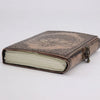 A leather notebook in antique grey with lotus mandala embossed on a copper-toned leather cover and brass clasp
