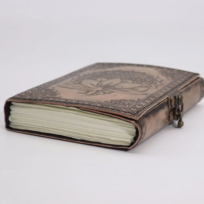 A leather notebook in antique grey with lotus mandala embossed on a copper-toned leather cover and brass clasp