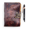 A leather notebook with a distressed brown leather cover embossed with the book of untold stories and a brass clasp