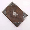 Brown leather notebook with silver embossed triple moon symbol and ornate corner details measuring 10 by 7 inches