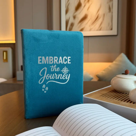 Light blue velvet notebook with embrace the journey embroidery compass rose and footprints on fabric cover