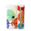 A lokta cotton notebook with colorful pressed leaves in green red orange and blue on a white base secured by twine and button