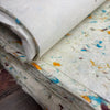 Stack of off-white lokta paper sheets with embedded blue orange and brown cotton fibres from green cotton packaging
