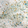 White lokta paper with textured surface and colorful cotton fibres in blue orange and brown from green cotton pack