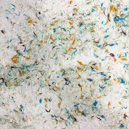 White lokta paper with textured surface and colorful cotton fibres in blue orange and brown from green cotton pack