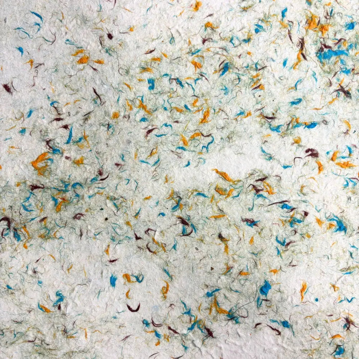 White lokta paper with textured surface and colorful cotton fibres in blue orange and brown from green cotton pack