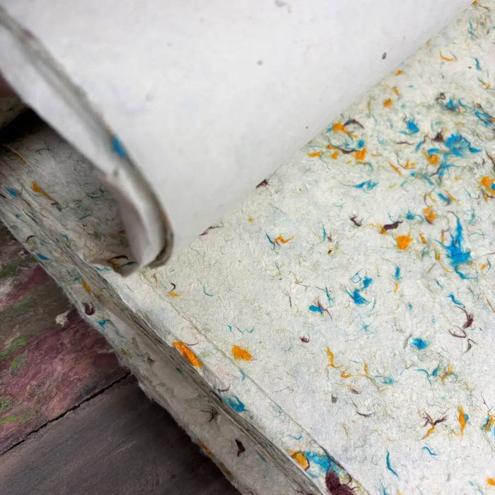 A roll of off-white lokta paper with blue orange and brown cotton fibres for green cotton craft and wrapping use