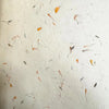 White textured lokta paper with embedded dried orange and gray flower petals in mixed floral cotton sheets