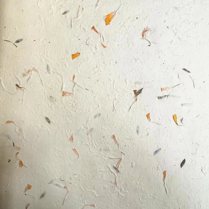 White textured lokta paper with embedded dried orange and gray flower petals in mixed floral cotton sheets