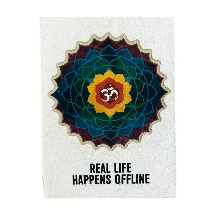 A textured white lokta paper notebook with a colorful mandala and om symbol titled real life happens offline