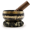 Black lotus flower singing bowl with gold trim and sanskrit script holds wooden mallet on a ring pillow