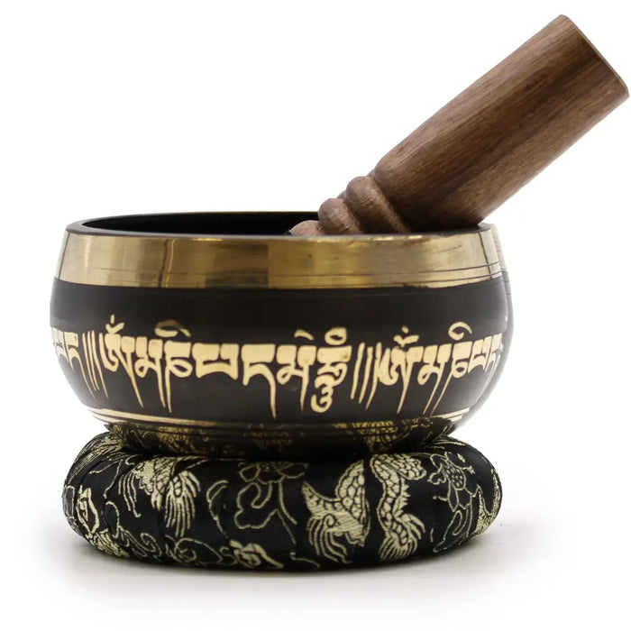 Black lotus flower singing bowl with gold trim and sanskrit script holds wooden mallet on a ring pillow