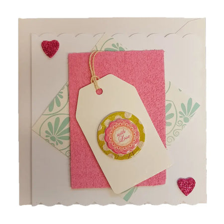 A cream paper tag with layered pink and yellow floral design on milford haven love themed greetings cards