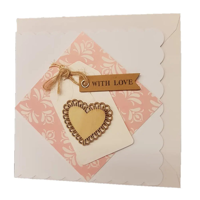 A cream paper love card with a laser-cut wooden heart over pink floral paper and a milford haven brown tag with twine