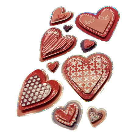 A collection of red and pink heart-shaped resin stickers with glittery edges and intricate swirl and dot patterns