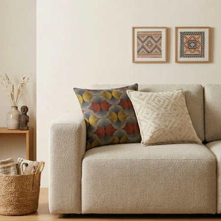 Beige textured fabric sofa with two cushion covers one colorful circular pattern and one embossed diamond design