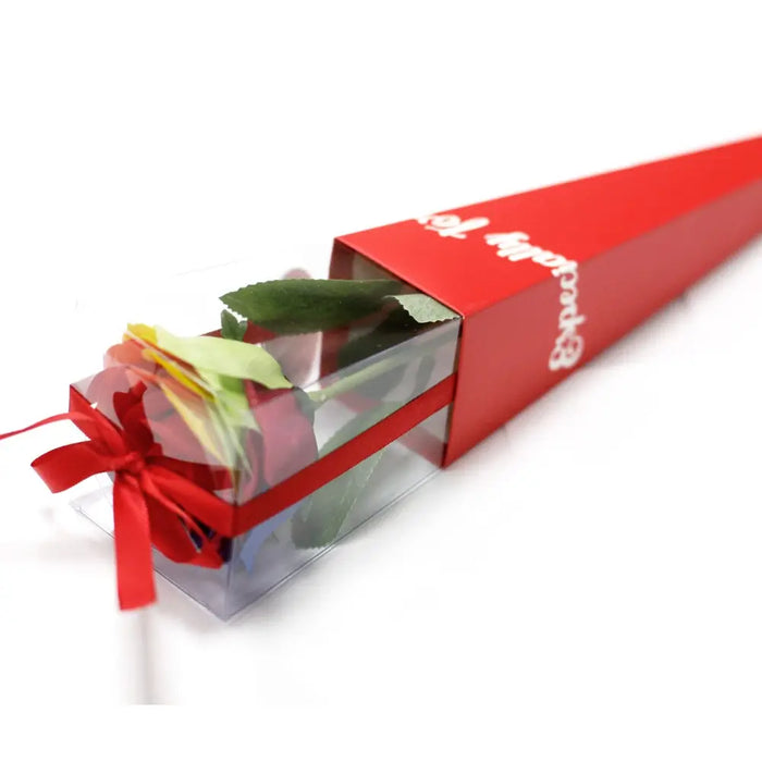 A luxury single soap flower red rose with green leaves wrapped in clear plastic and red ribbon inside a red box