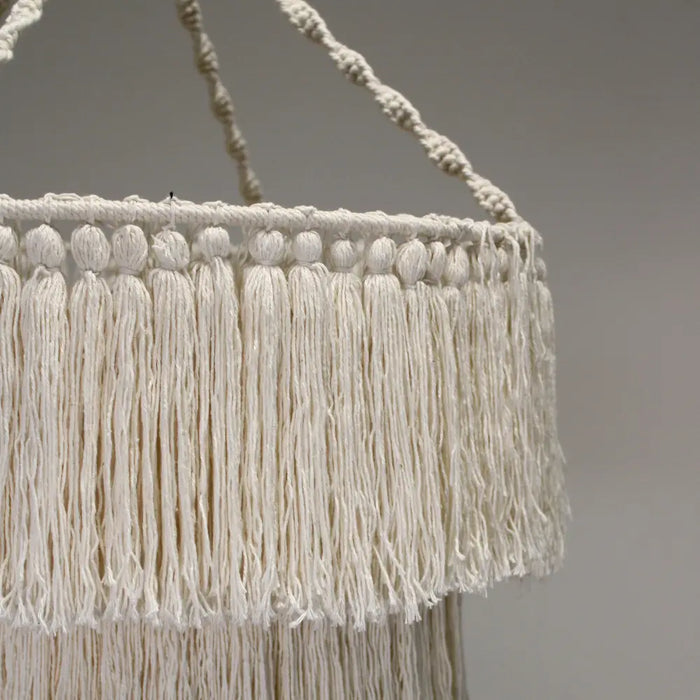 Cream-colored macrame chandelier made of soft cotton rope with intricate woven cords and long fringe hanging decor