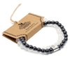 Black and white magnetic gemstone bracelet with a silver toned rectangular charm engraved with a design