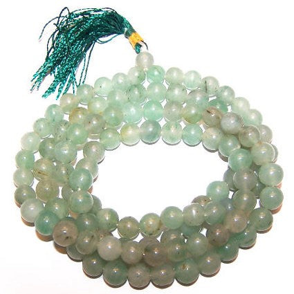 A coiled strand of translucent green aventurine mala beads with a teal tassel at the top