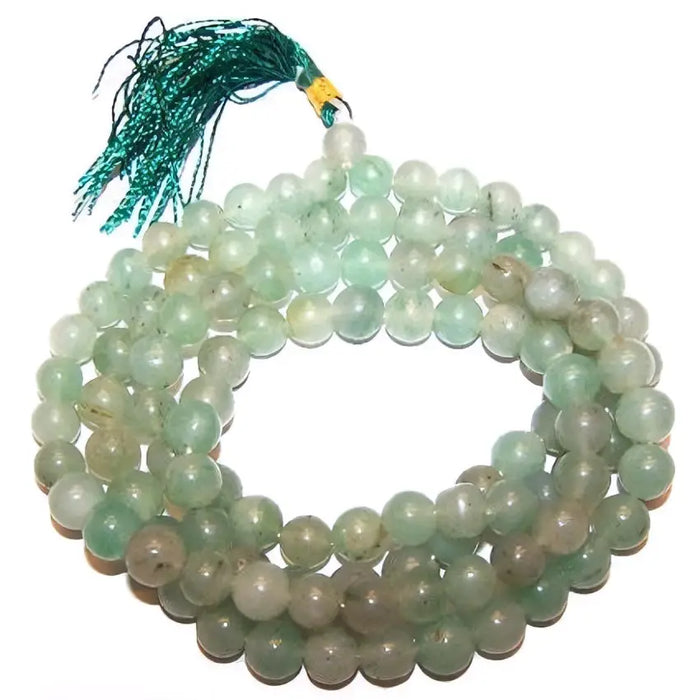 A coiled strand of translucent green aventurine mala beads with a teal tassel at the top