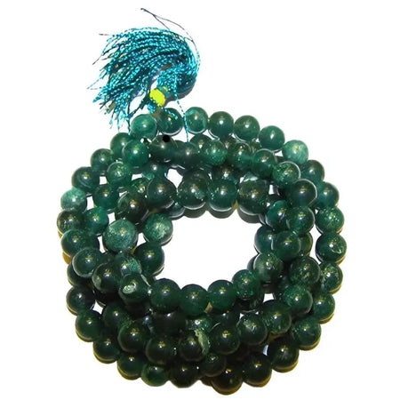 A coiled string of deep green jade mala beads with polished stones and a teal tassel at the top