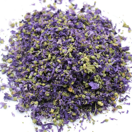 A pile of dried mallow flowers whole blue in purple and green shades likely used for herbal purposes