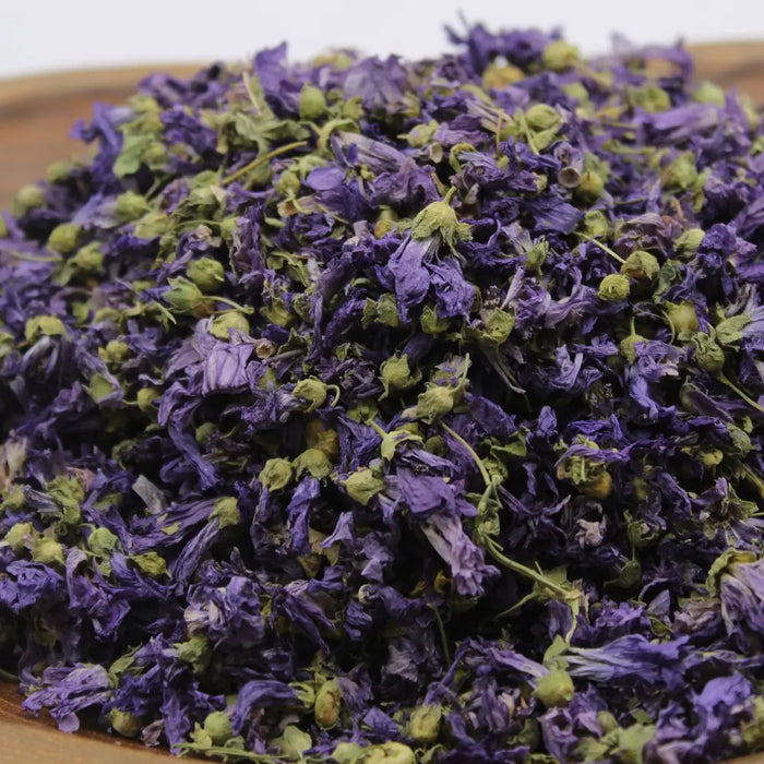 A pile of dried purple and green whole mallow flowers used as herbal tea blend weighing 0.5kg