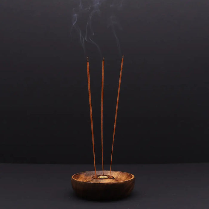 Wooden mango wood incense stick and cone burner disc with three brown sticks emitting smoke and a buddha symbol
