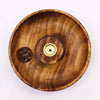A round mango wood incense burner disc with natural grain finish, om symbol engraving, and brass incense holder