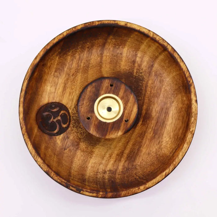 A round mango wood incense burner disc with natural grain finish, om symbol engraving, and brass incense holder