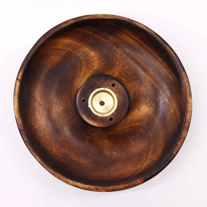 A dark brown mango wood incense burner disc with a brass center piece for wood incense sticks and cones