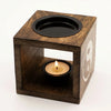 Dark mango wood oil burner cube with yin yang symbol and black top holding a lit tealight candle inside