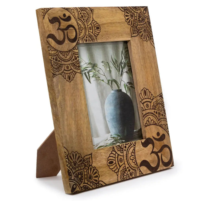 A rustic mango wood picture frame with dark brown engraved om mandala patterns and natural wood grain finish