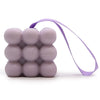 Lavender-colored cube massage soap with a bubbly texture and a purple ribbon loop for hanging and easy use