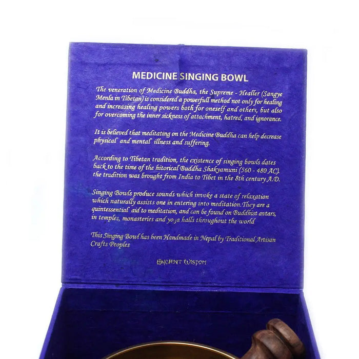 A golden medicine buddha singing bowl made of metal nestled in a deep blue velvet box handcrafted by nepali artisans