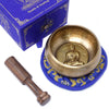 Golden medicine buddha singing bowl with hammered texture and embossed buddha on blue embroidered mat 10cm